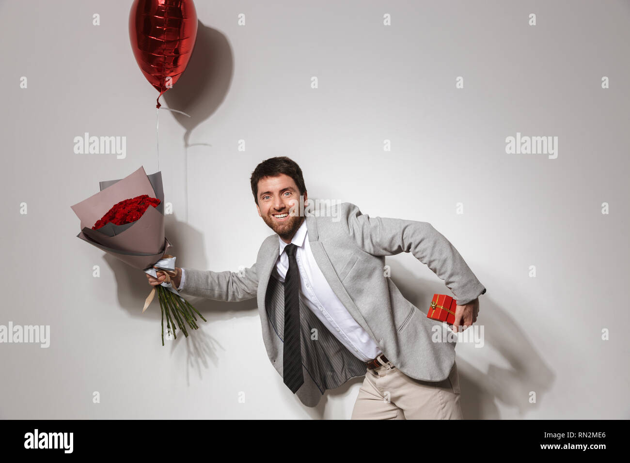 Portrait of a handsome confident young man wearing suit running ...