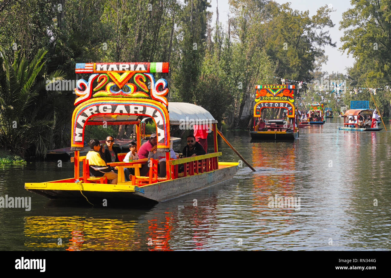 Tourists in uniquely named trajinaras cruising the floating gardens of Xochimilco at Mexico city. Stock Photo