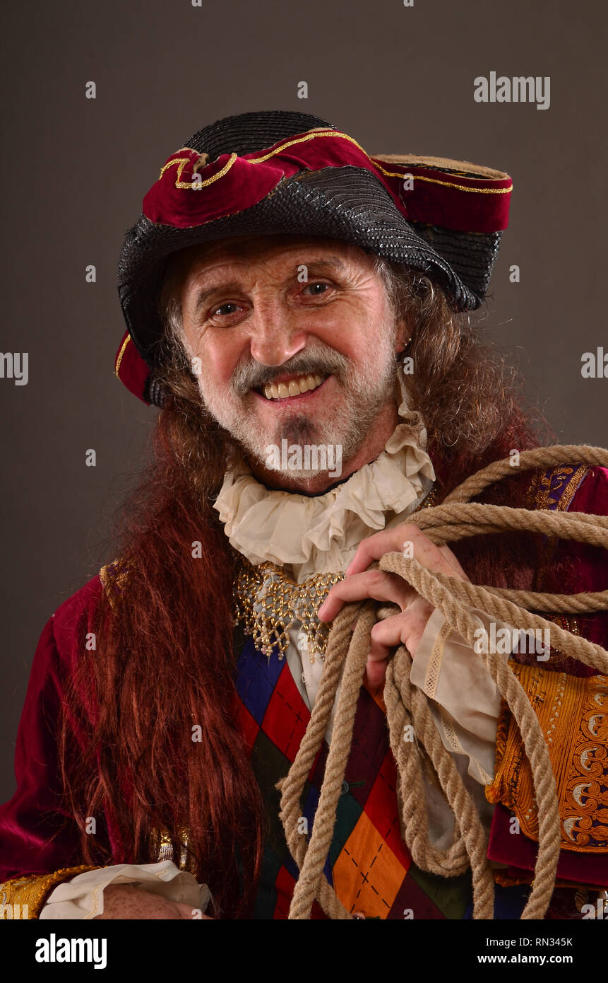 Portrait of smiling old redhead pirate holding rope, studio shot Stock Photo