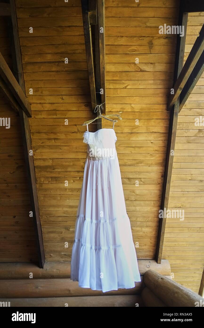 wedding dress on a hook on a wooden covering Stock Photo