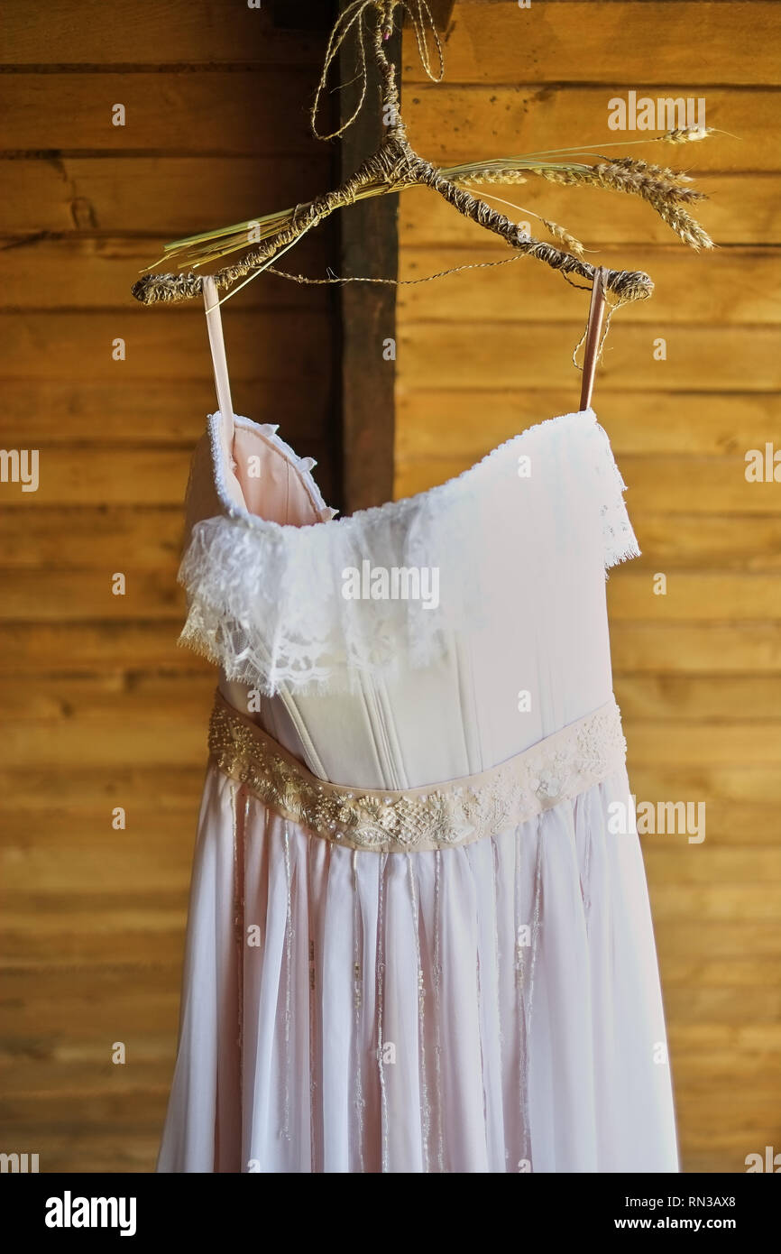 wedding dress on a hook on a wooden covering Stock Photo