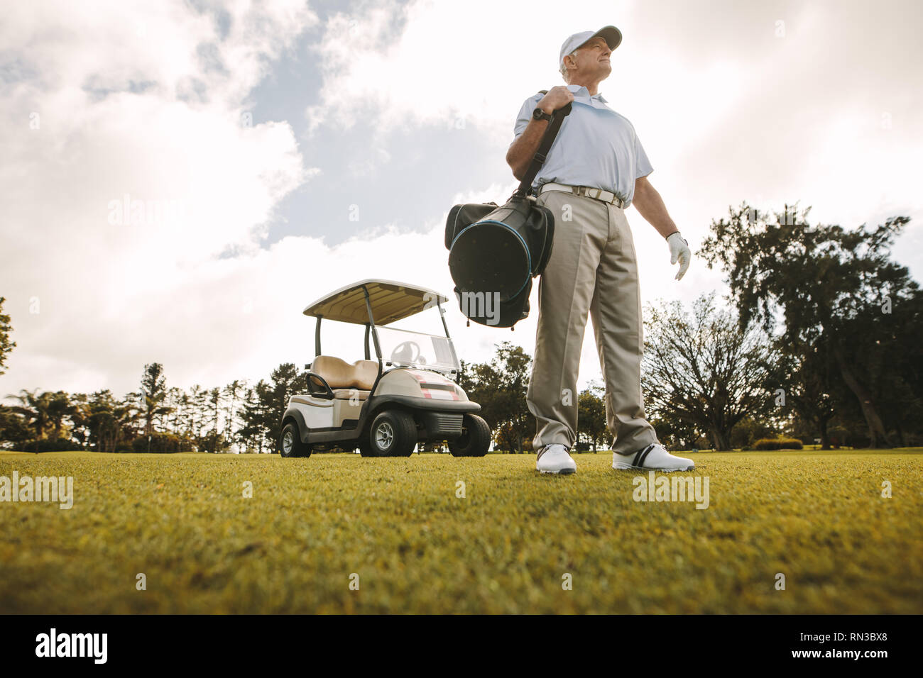 Low angle shot of senior male golfer standing on the golf course with