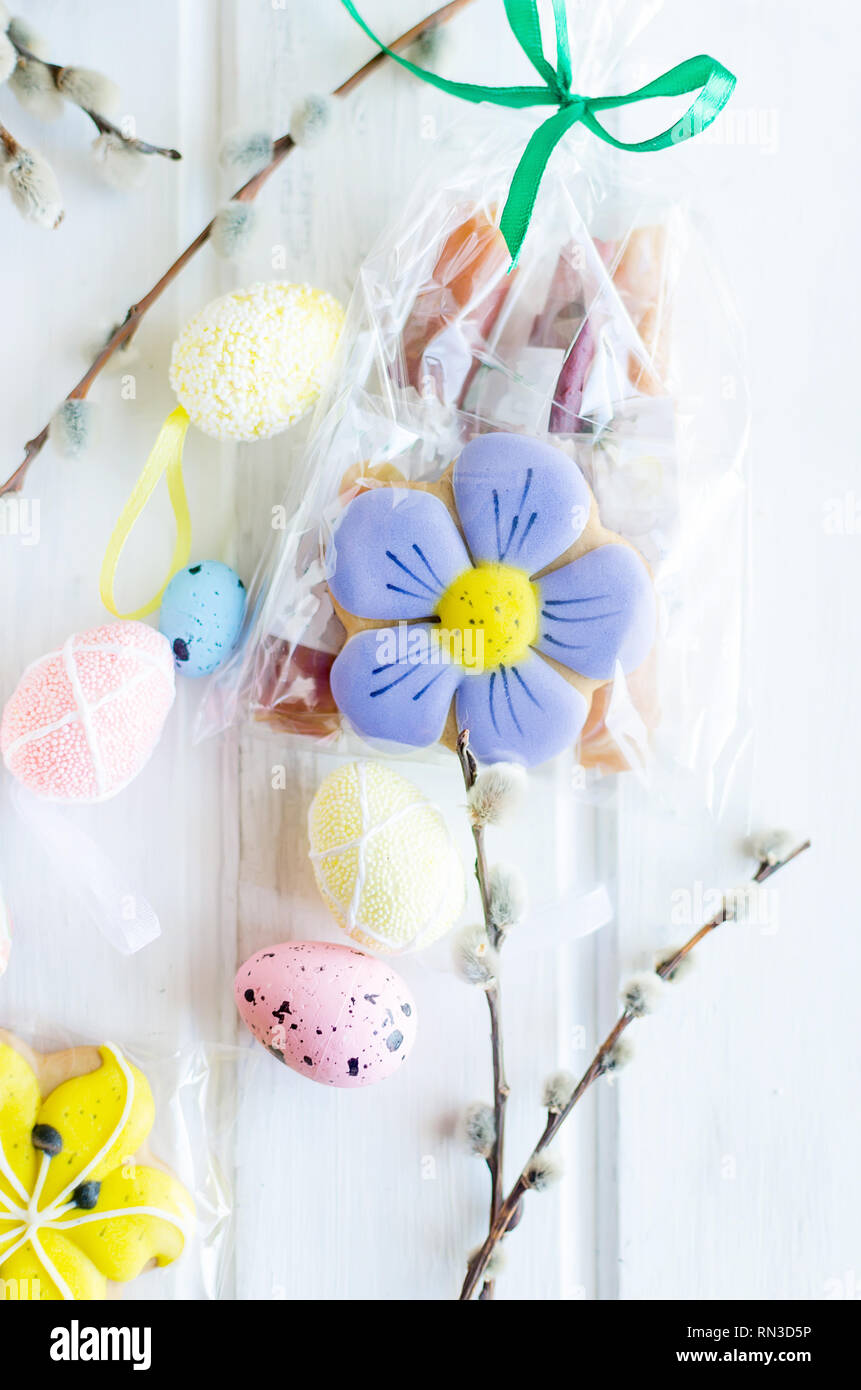 yellow tulips, ginger cookies, willow twigs, decorative eggs in a tray laid out on a white old wooden table, easter holiday background with sweets, fl Stock Photo