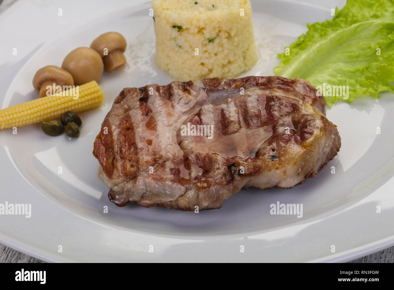 Grilled pork neck steak served pickled vegetables and couscous Stock