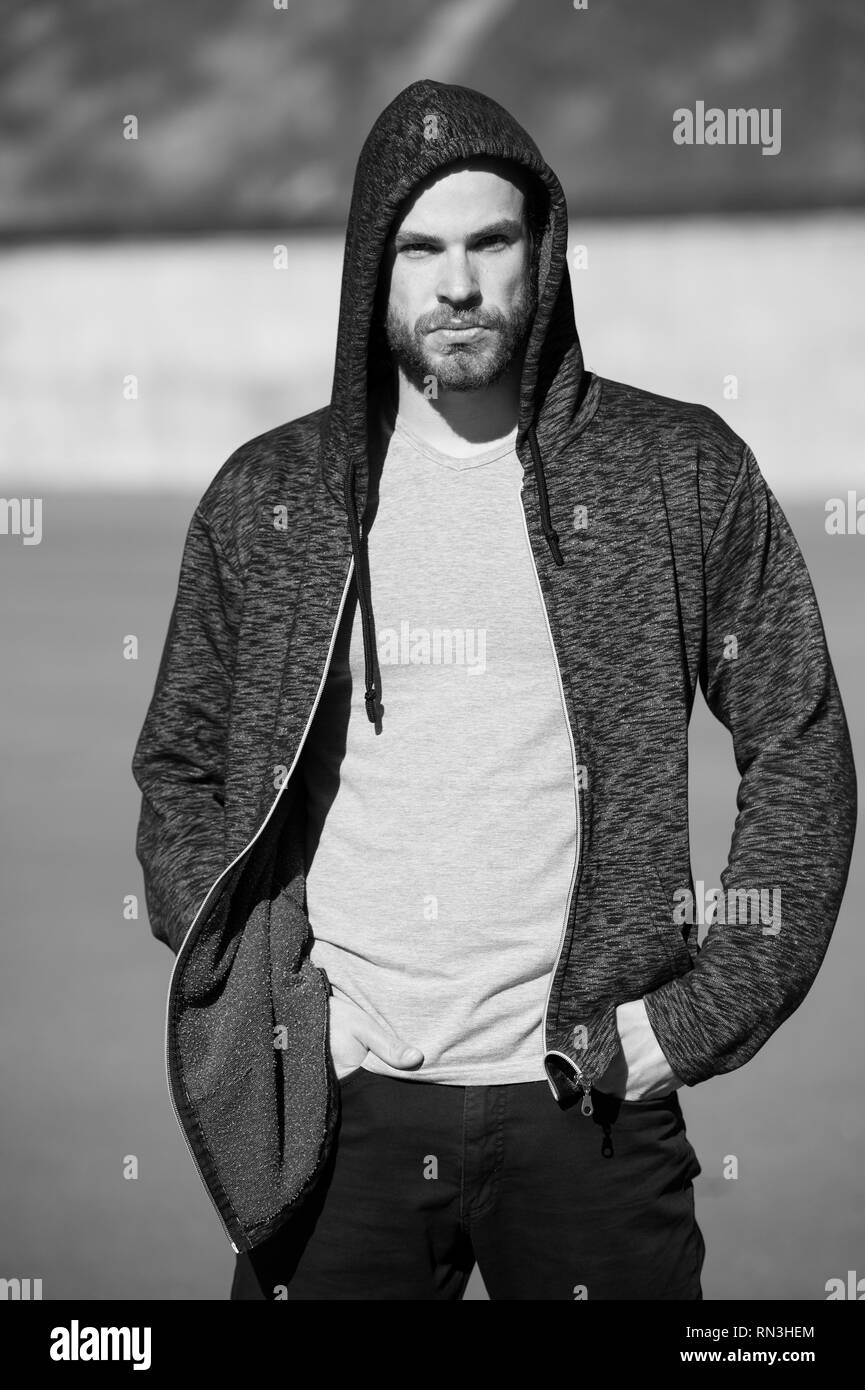 man with beard wearing sportswear fashion, caucasian man, black hoodie and grey shirt, sunny outdoor on blurred background, black and white Stock Photo