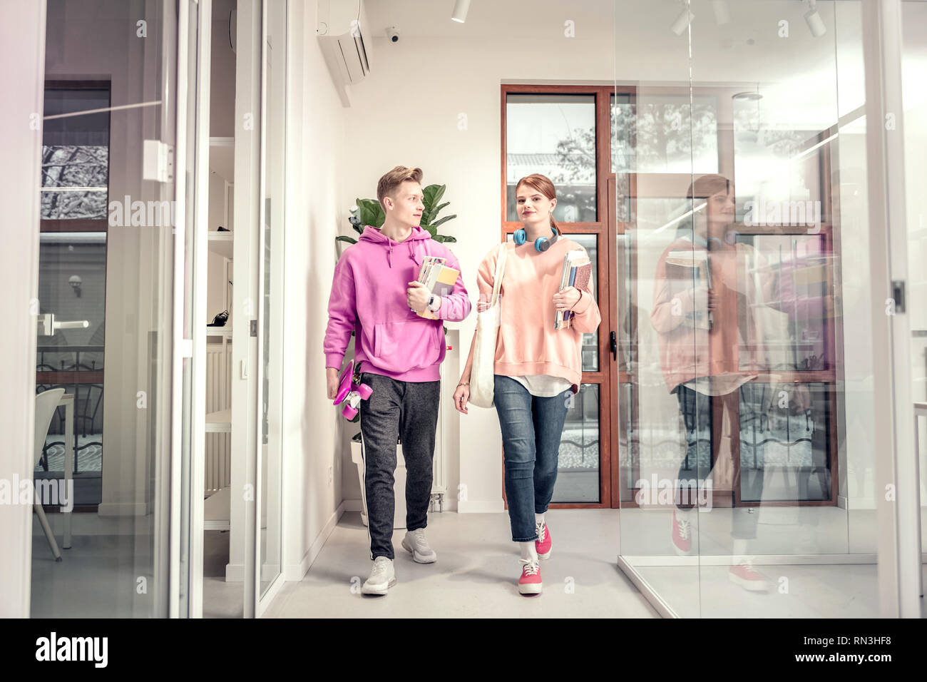 Couple of students wearing jeans and hoodies going to class Stock Photo