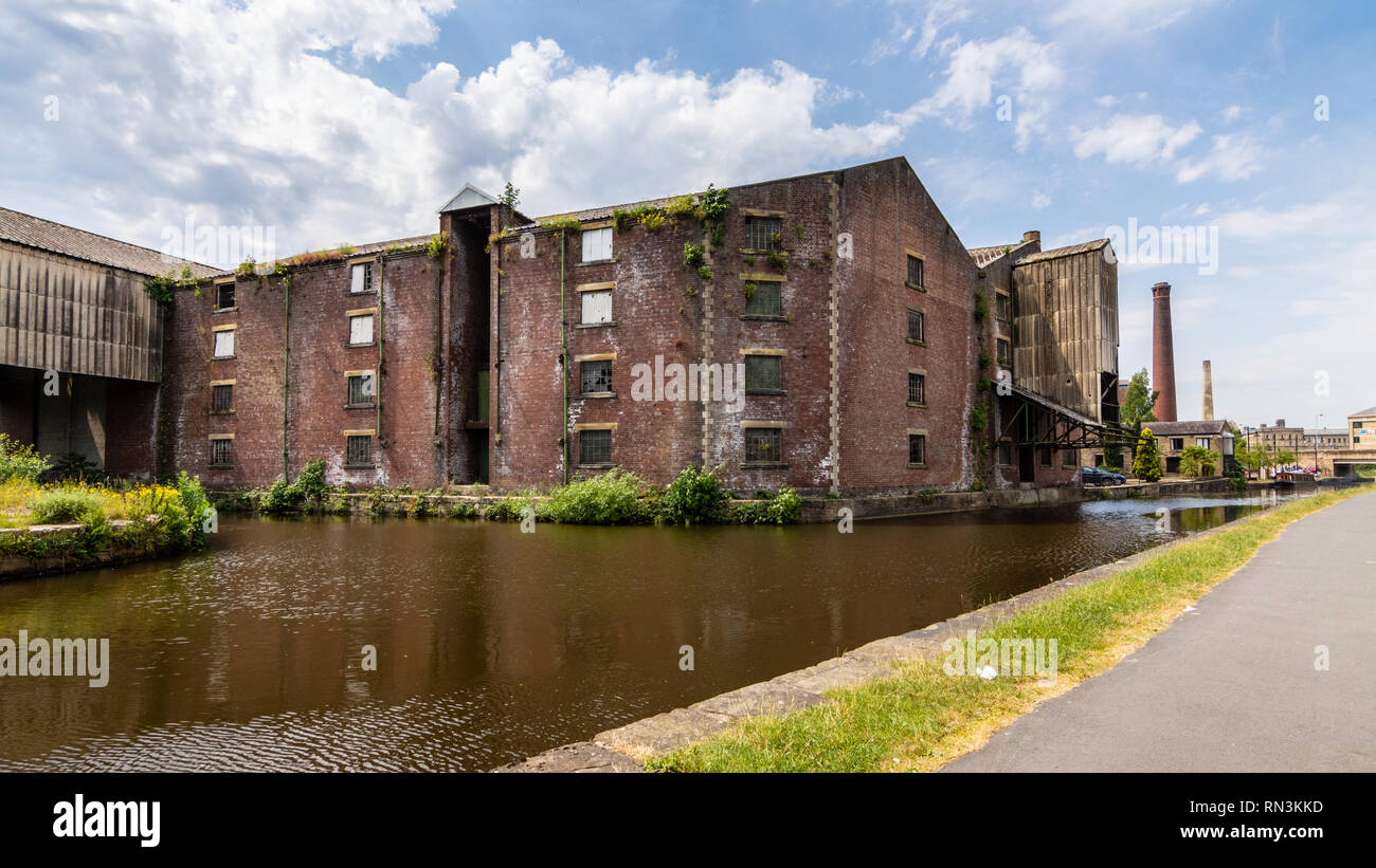 Shipley, England, UK - July 1, 2015: Traditional old factory mills and warehouses stand derelict on Merchants Quays beside the Leeds and Liverpool Can Stock Photo