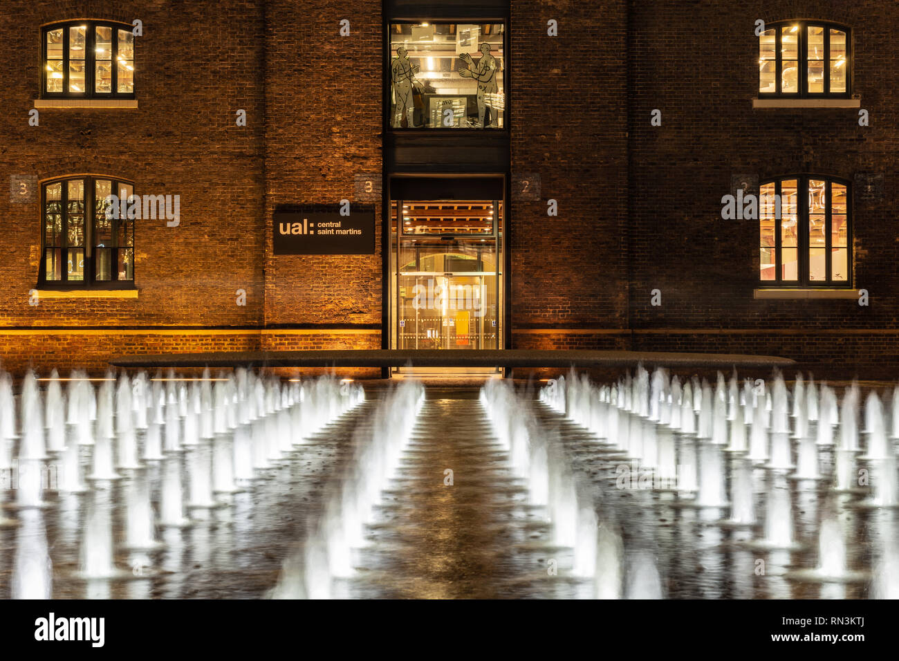 London, England, UK - December 20, 2018: Fountains are lit at night in Grannary Square outside Central Saint Martin's College of the University of the Stock Photo