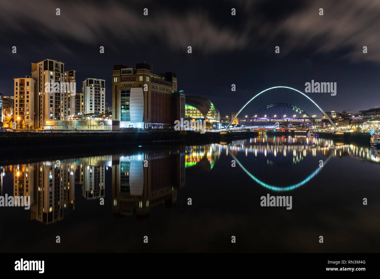 Gateshead, England, UK - February 3, 2019: Gateshead's Millennium Bridge, Baltic Flour Mills, Sage and modern apartment buildings are reflected in the Stock Photo