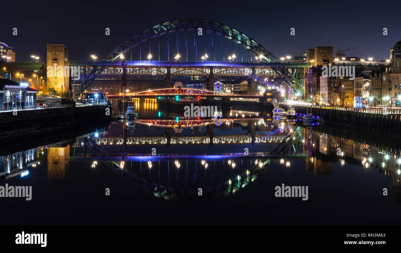 Newcastle, England, UK - February 3, 2019: Bridges between Newcastle and Gateshead are lit at night and reflected in the waters of the River Tyne. Stock Photo