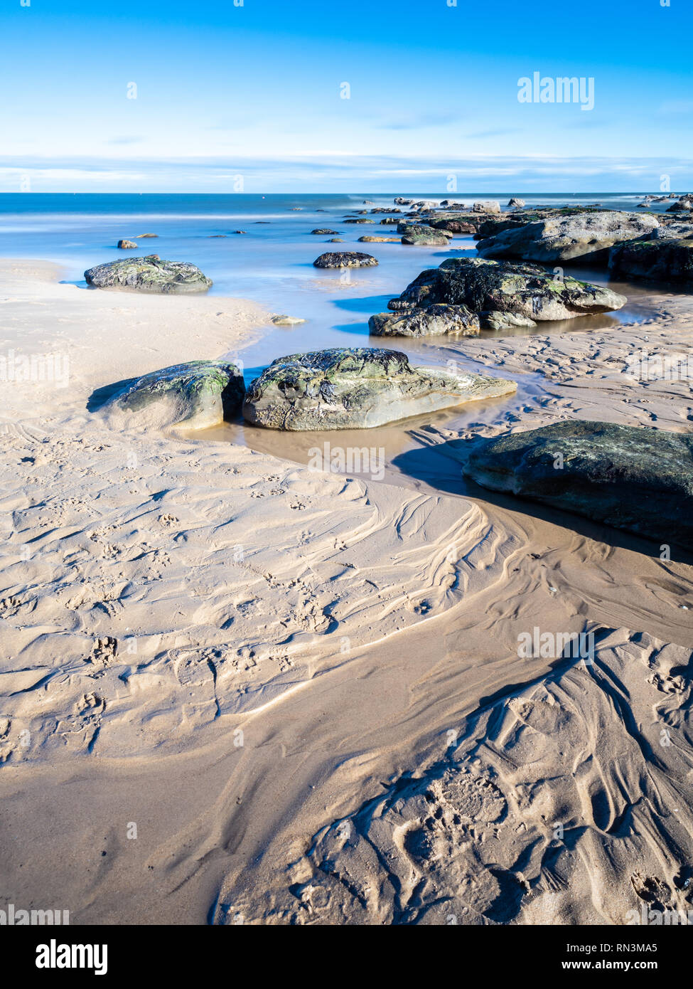 Small streams and rocks create patterns in the sands of Longsands Beach at Tynemouth. Stock Photo