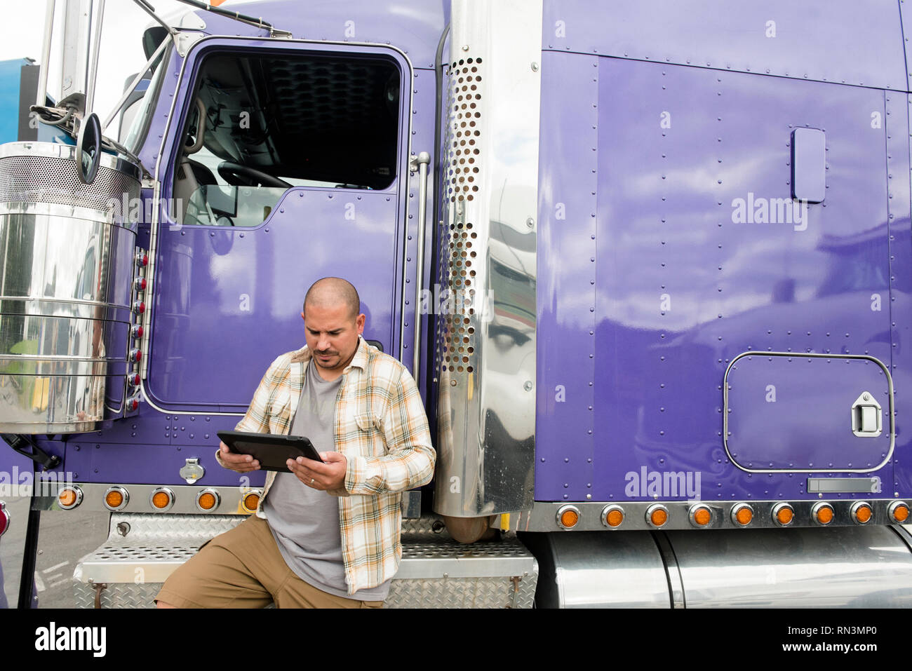 Truck driver working on digital tablet by his semitruck Stock Photo
