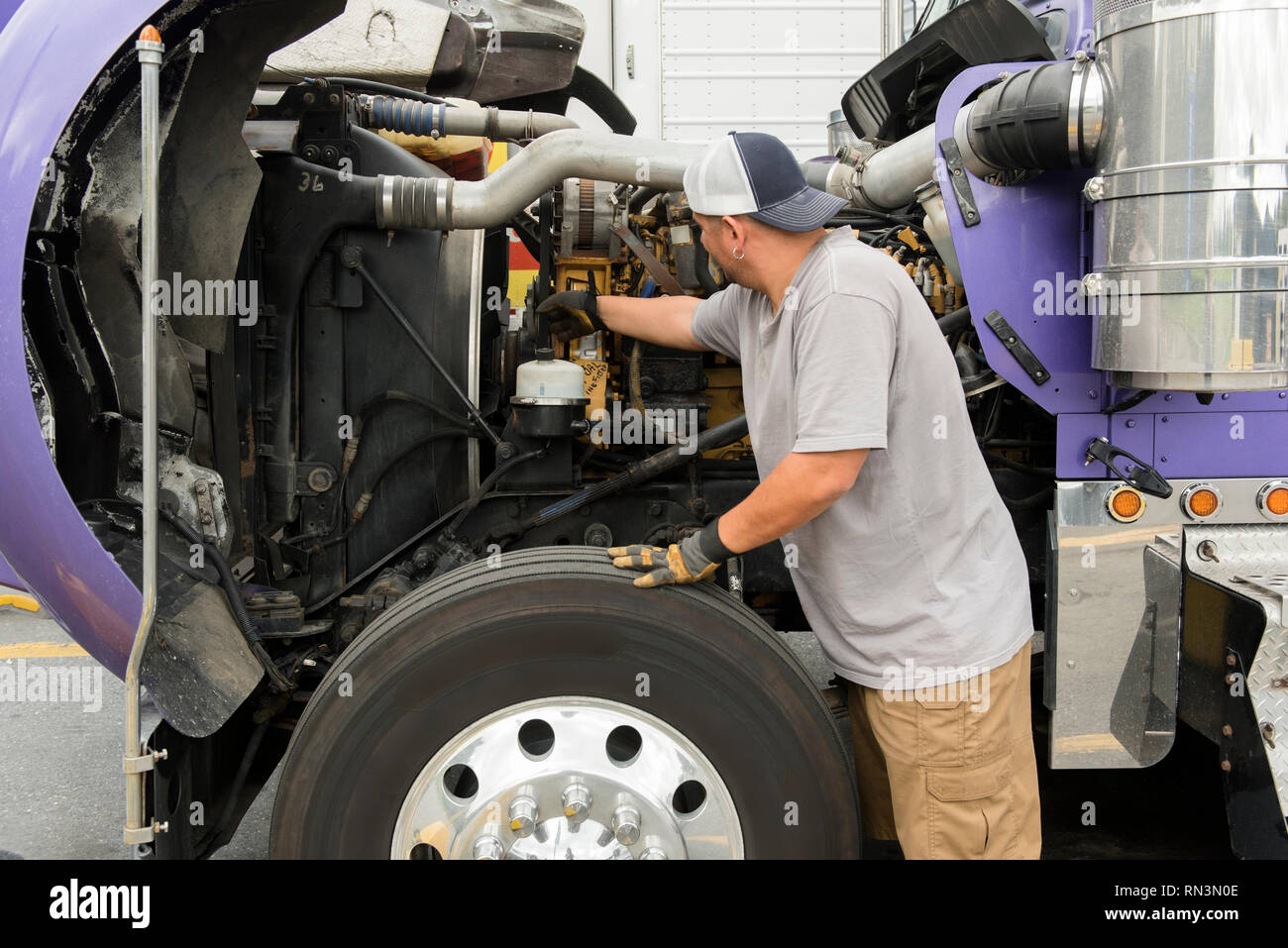 Truck driver checking semi-truck engine Stock Photo