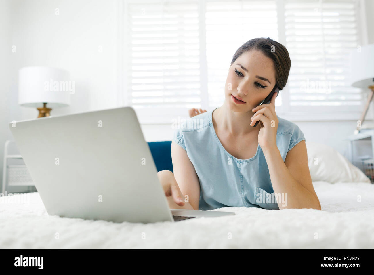 Young woman using laptop on bed Stock Photo