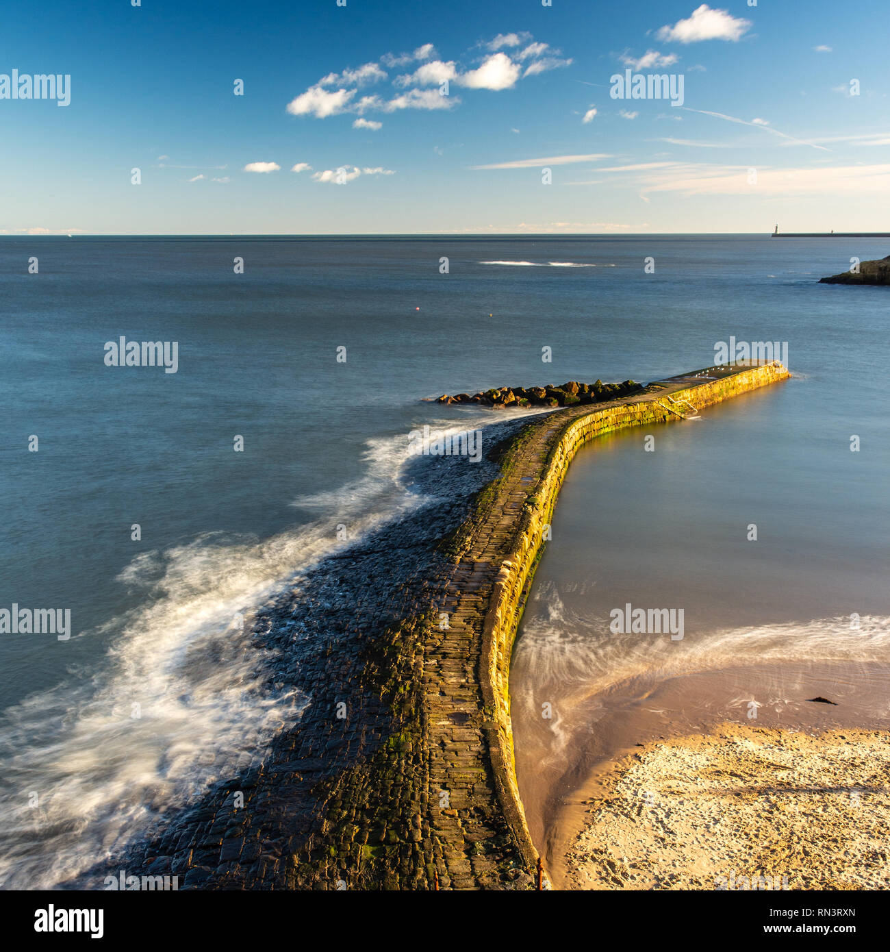 Waves break on the stone harbour wall of Cullercoats Bay on Tyneside's North Sea Coast. Stock Photo