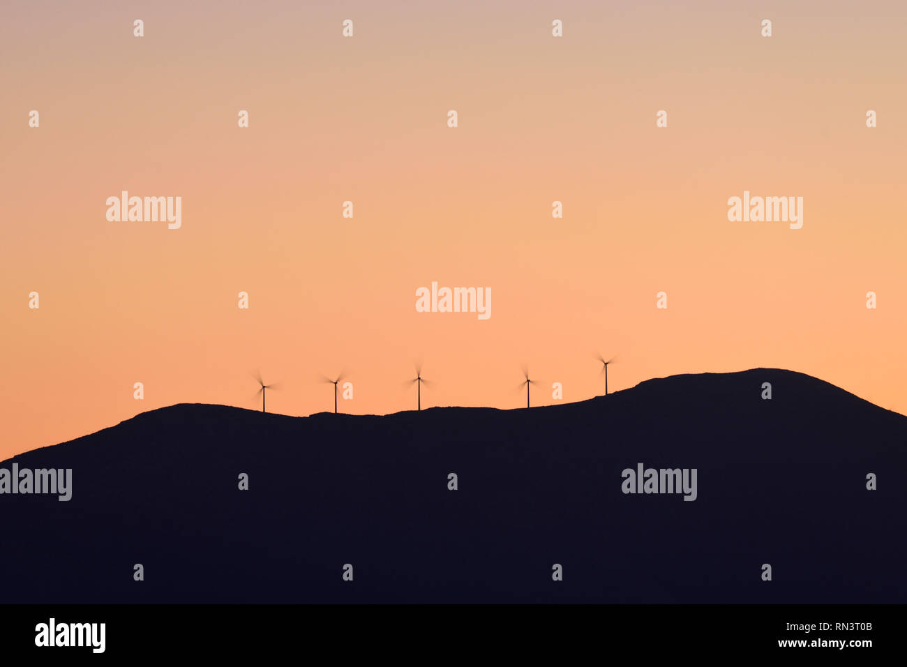 Silhouette of wind turbines on hill at sunset Stock Photo - Alamy