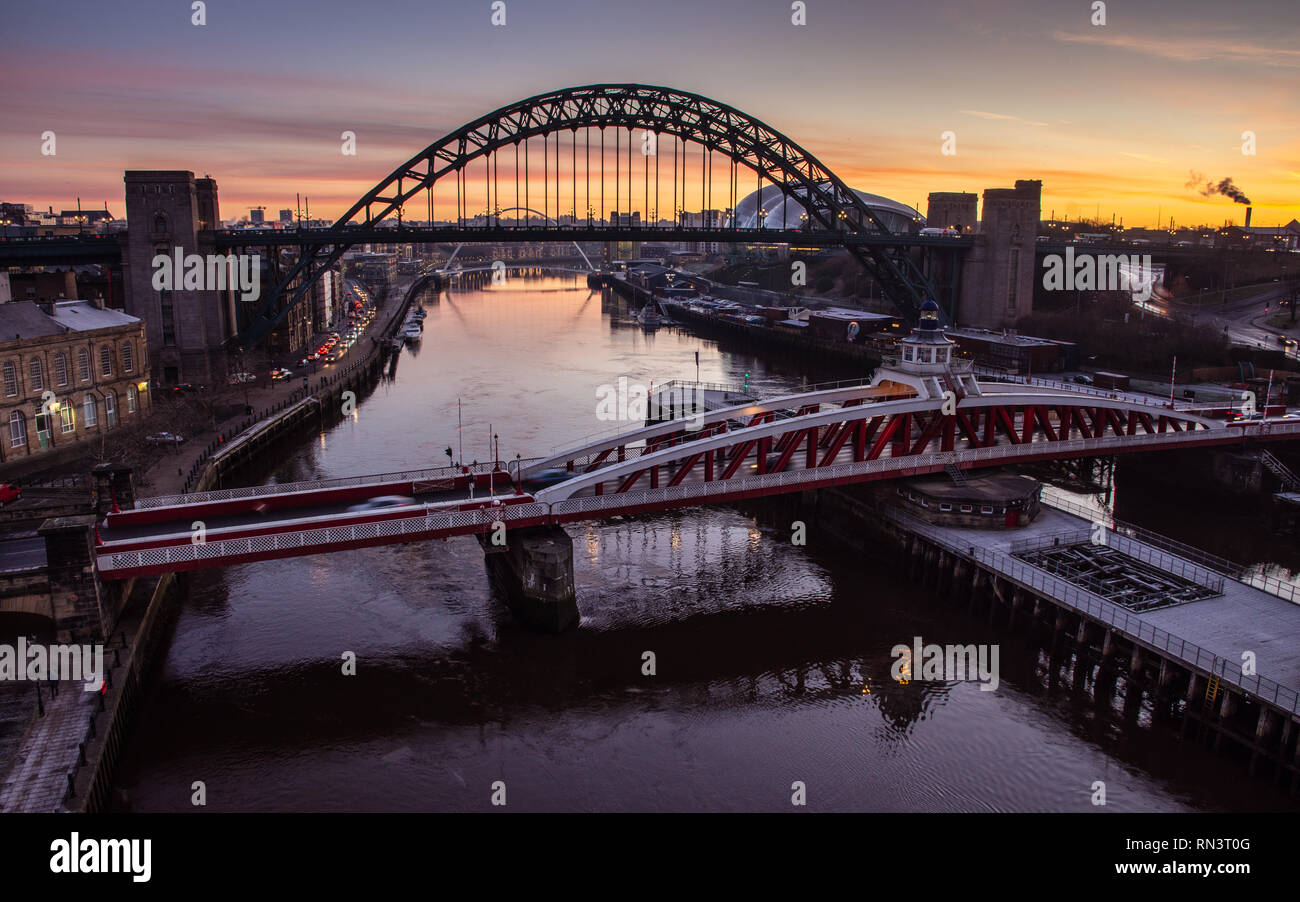 Newcastle, England, UK - February 5, 2019: The sun rises behind the iconic Tyne Bridge and swing bridge between Newcastle and Gateshead on the River T Stock Photo