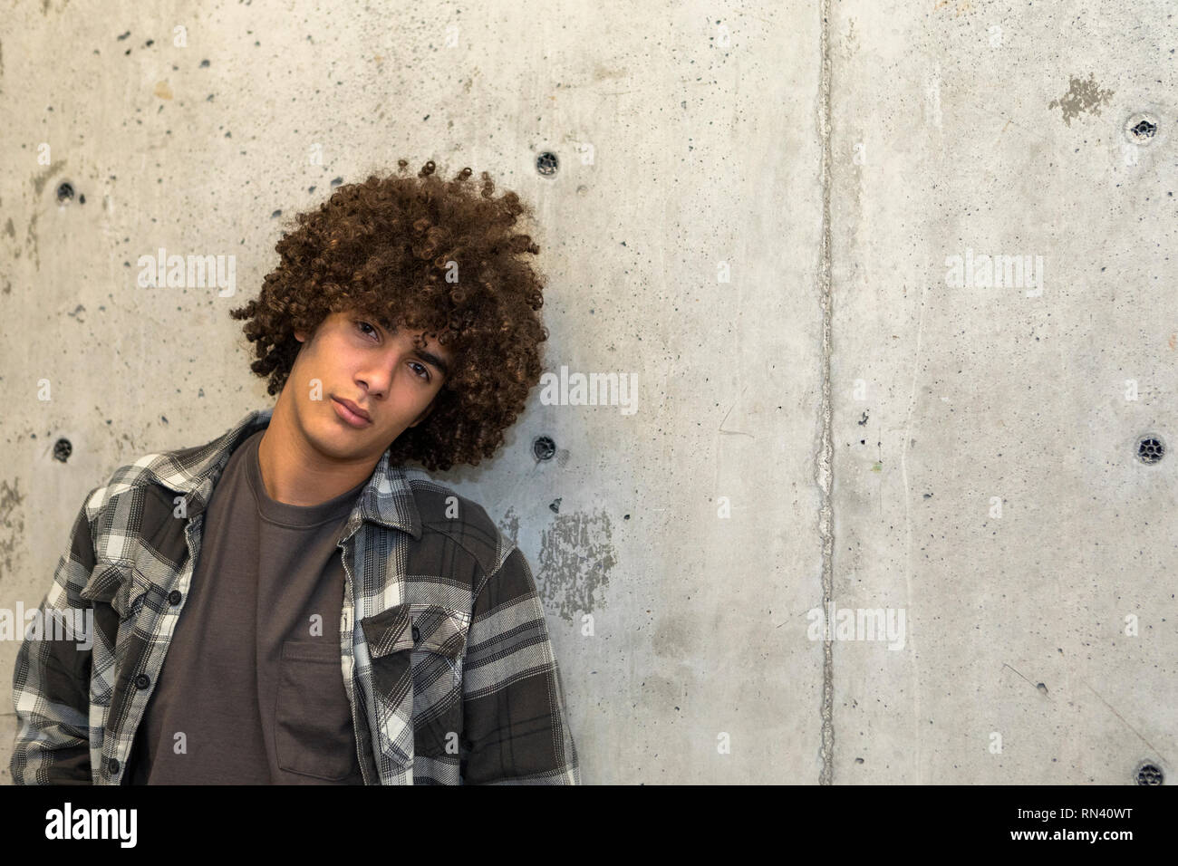 Portrait of teenage boy by concrete wall Stock Photo - Alamy