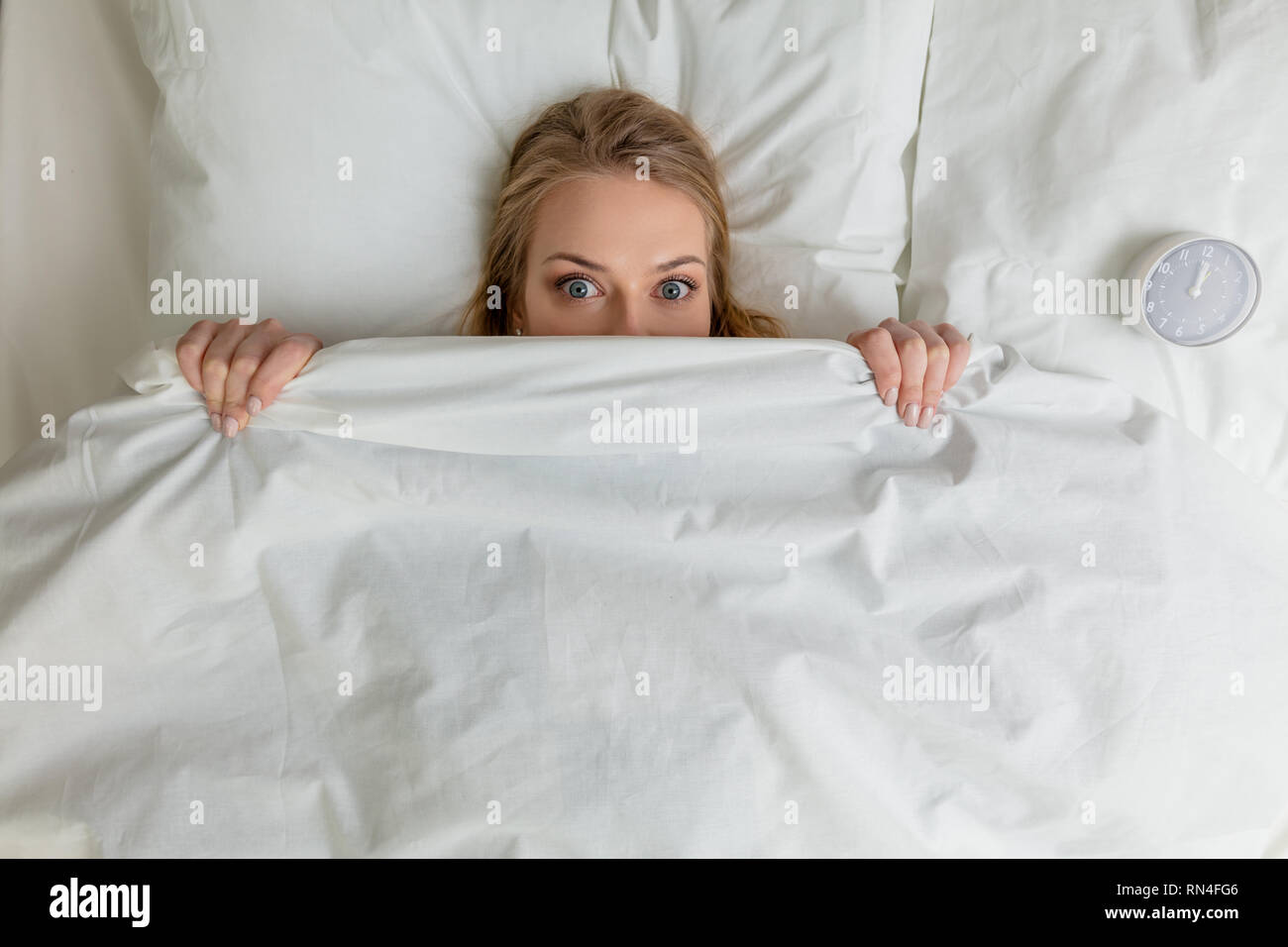 pleasant blonde girl hiding under the blanket and looking at the camera,  fobia, emotion, feeling. top view photo Stock Photo - Alamy