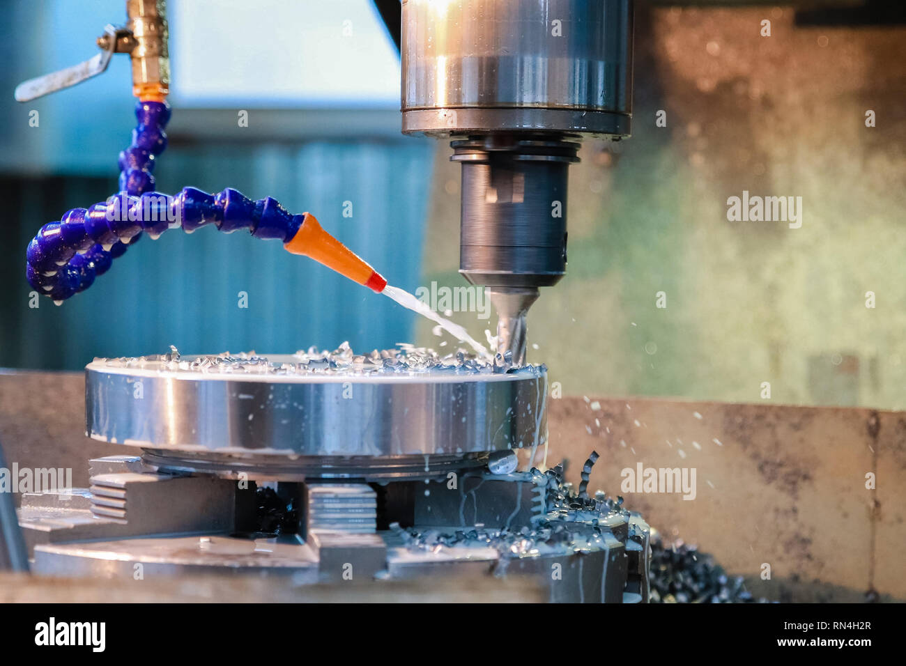 Drilling machine makes a hole in the metal product. Coolant is pouring on the drill. Stock Photo
