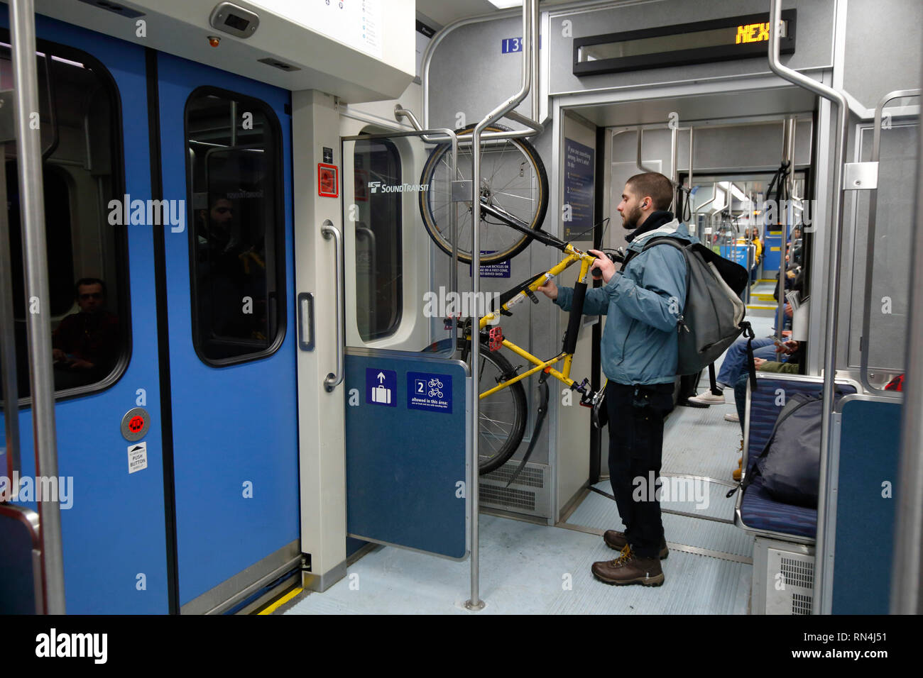 A Seattle bicyclist stows a bicycle at a designated holding area inside a Sound Transit Link light rail car Stock Photo