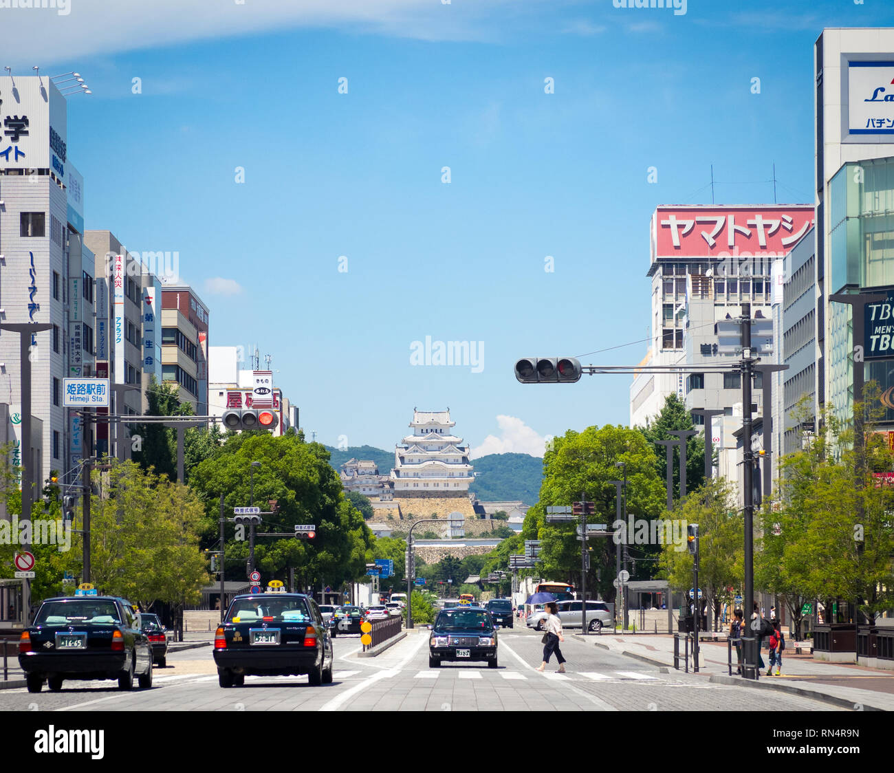 A view of Ootemae-dori (Ootemae Street), the main street, and Himeji Castle (Himeji-jo) rising in the background, in Himeji, Hyogo Prefecture, Japan. Stock Photo