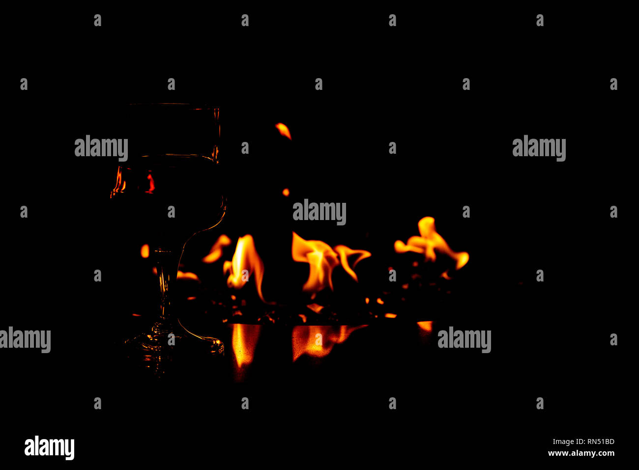 A Glass Of Red Wine Sitting On The Rim Of Fire Pit With The Flames