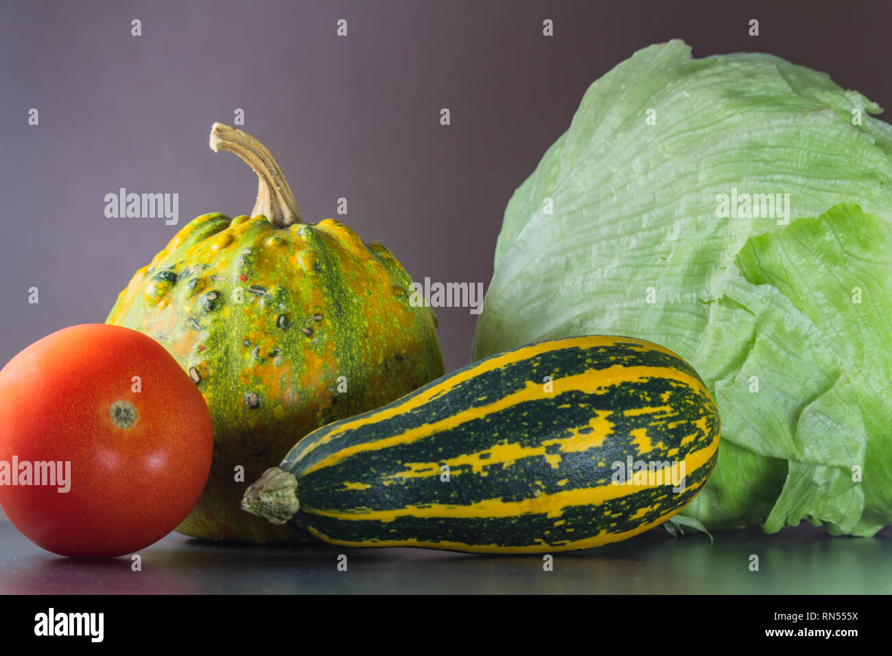 Two green and orange pumpkin on stone desk with tomato and lettuce Stock Photo