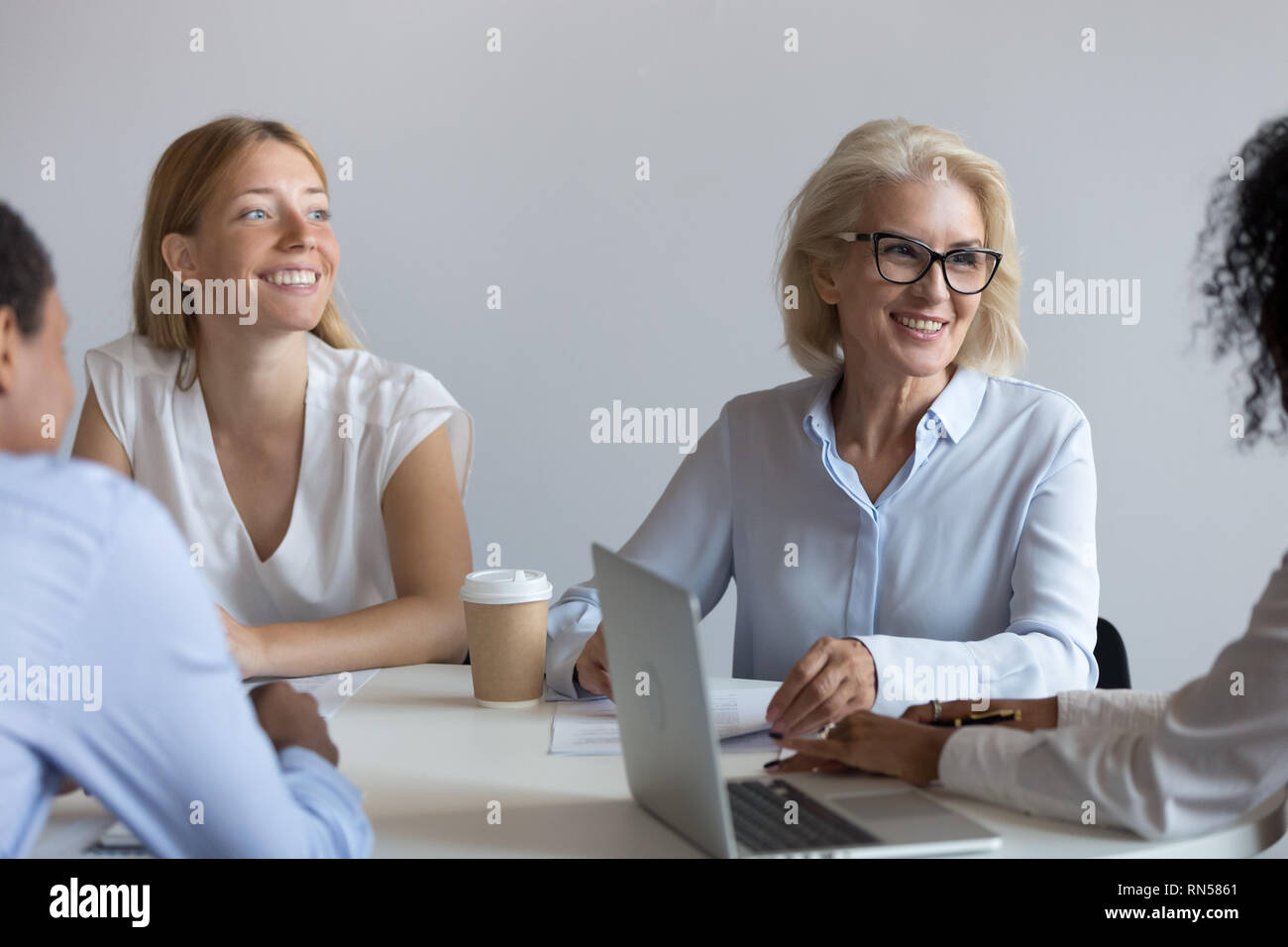 Aged business coach provides information to interns young company staff Stock Photo