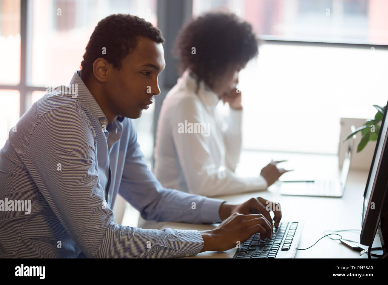 Serious african employee working on computer at coworking space Stock Photo