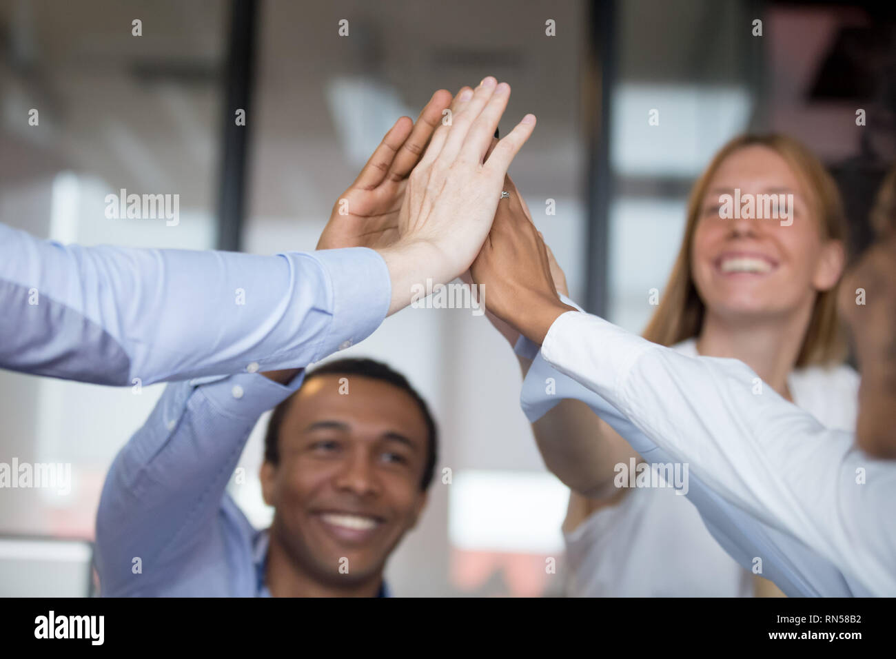 Happy diverse businesspeople giving high five closeup focus on hands Stock Photo
