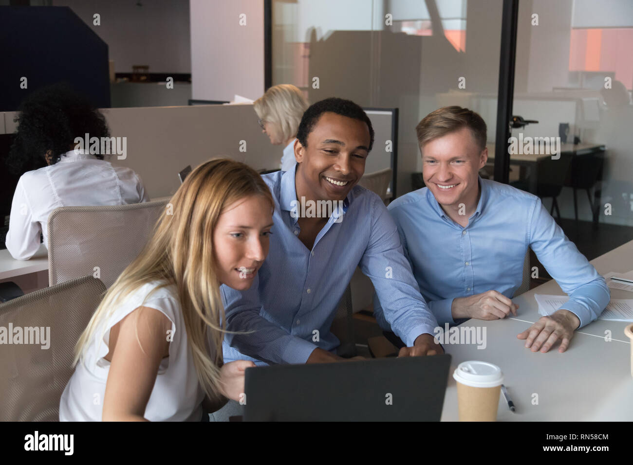 Three cheerful employees working at coworking room using computer Stock Photo