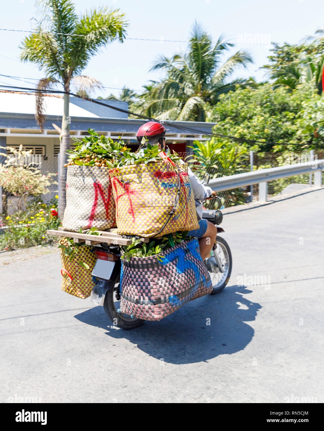 MY THO, VIETNAM - FEBRUARY 24, 2018: Cyclist transports fruits on motorcylce in My Tho, Vietnam Stock Photo