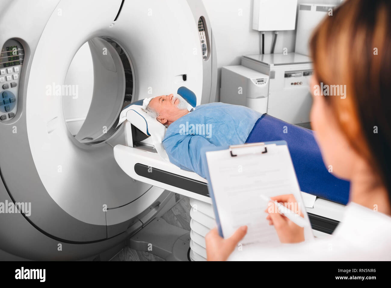 doctor write into medical chart after CT Scan Stock Photo