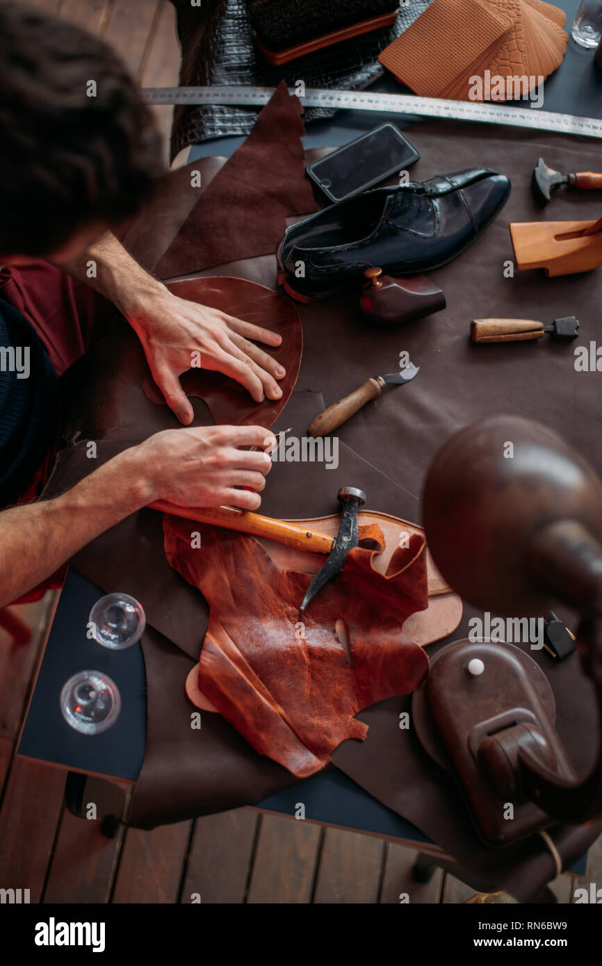 messy shoemaker's table , man concentrated on mending shoes, close up