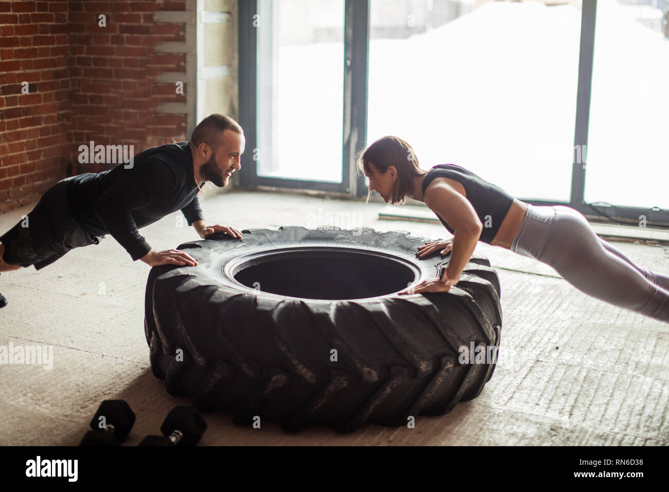 Young trained caucasian woman in sportswear makes push-ups on truck tire  with personal trainer assistance and supervision Stock Photo - Alamy