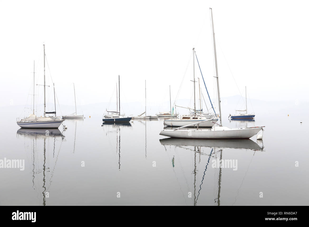 boats that are reflected on the water, in the fog and in the sun Stock ...