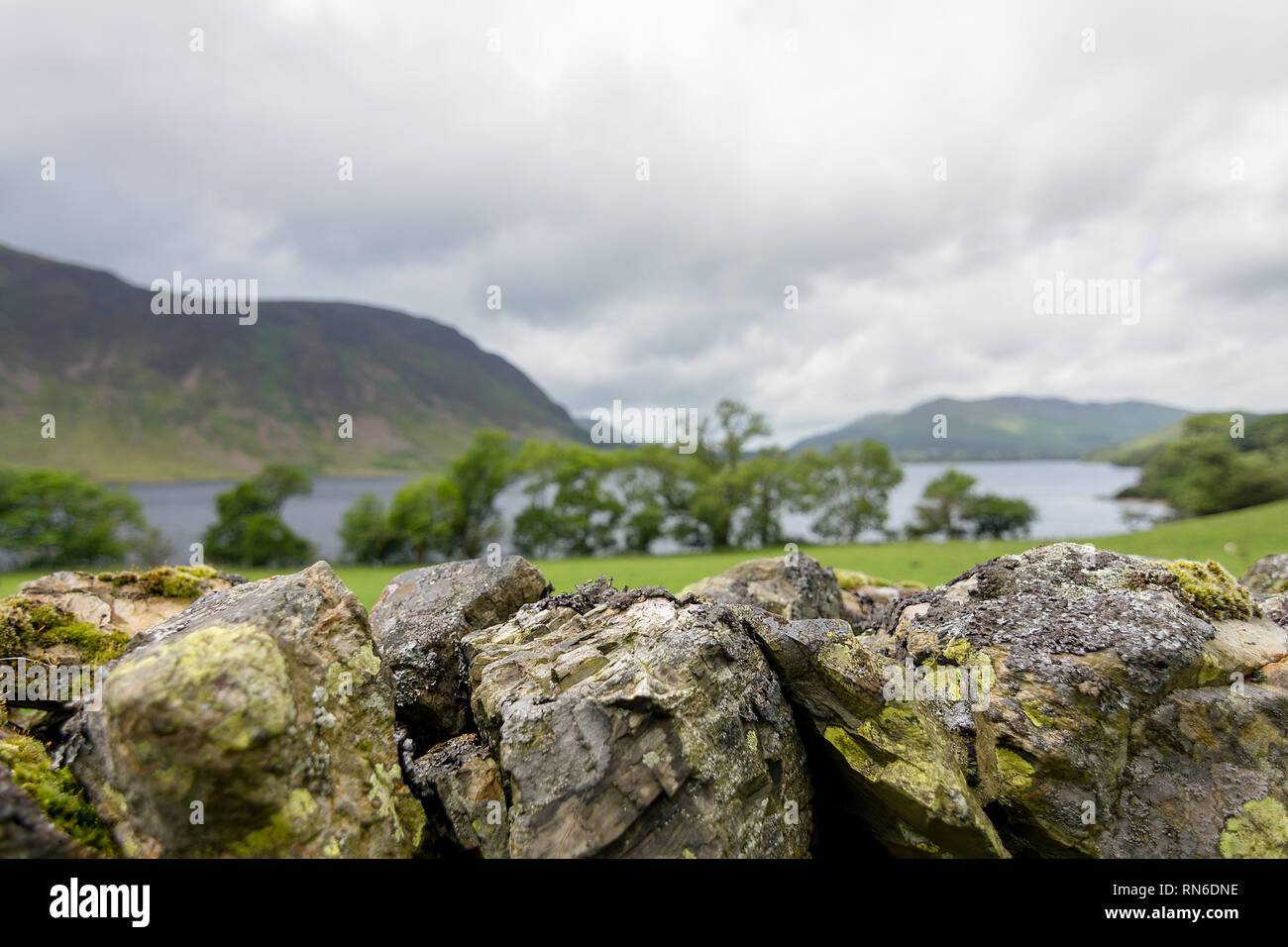 A dry stone wall of Lake District stone with back drop of trees, lake and hills of Cumbria, England. Stock Photo