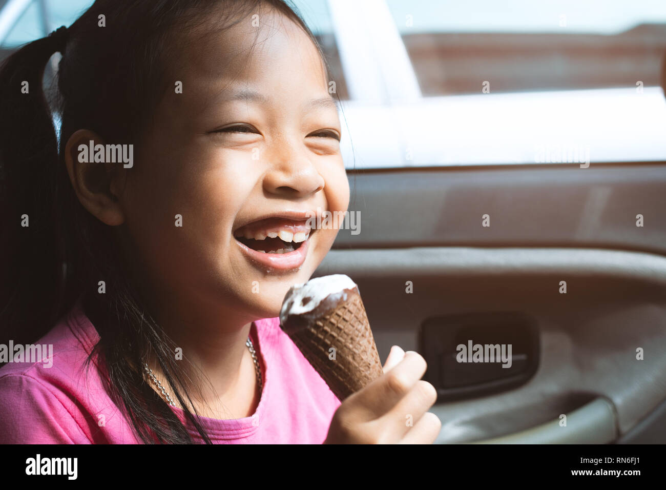 Asian child girl eating ice cream in car with smile and happy Stock Photo