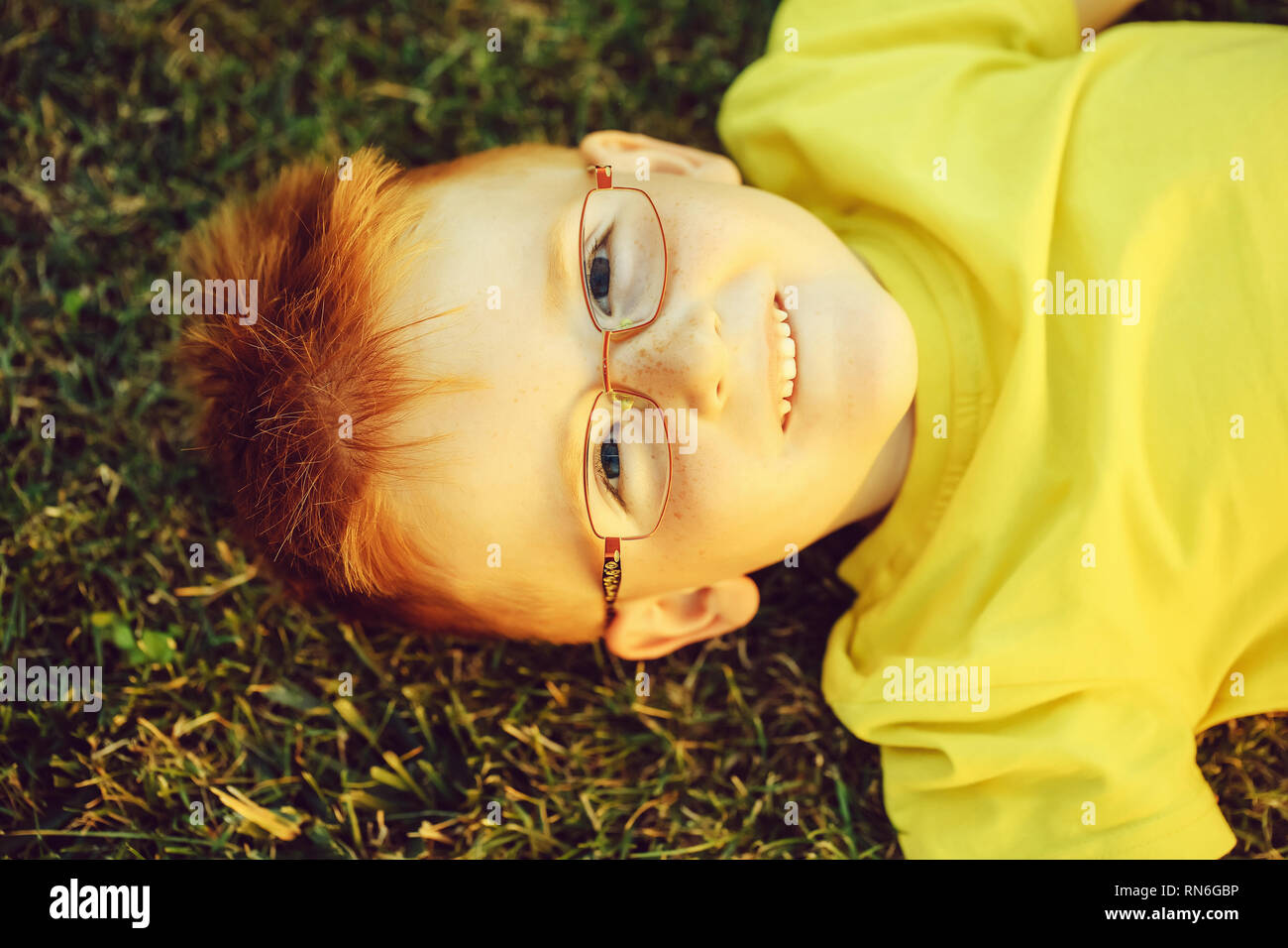 Happy baby boy with red hair in glasses on grass Stock Photo - Alamy