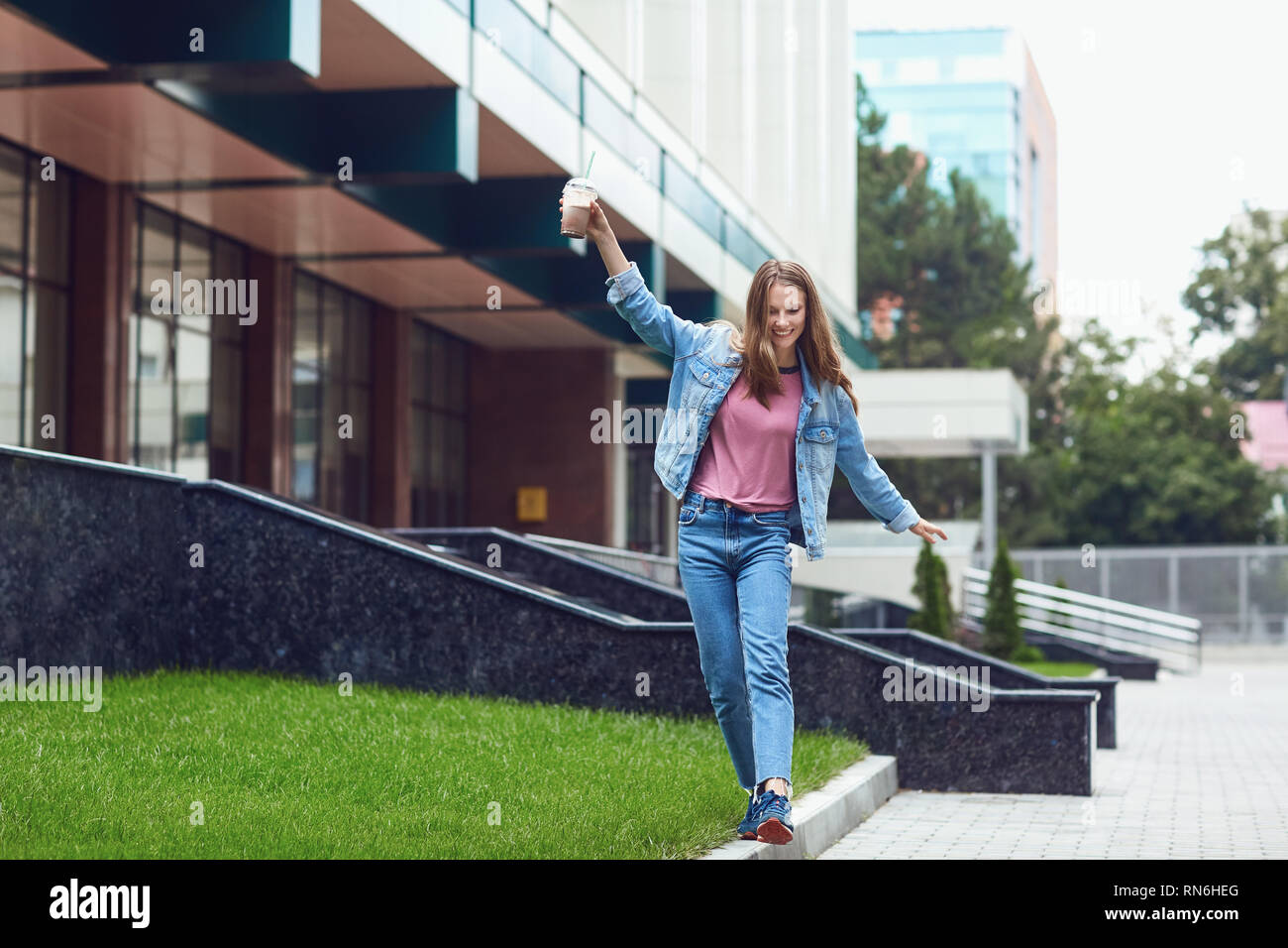 Playful woman walking on pavement border Stock Photo - Alamy