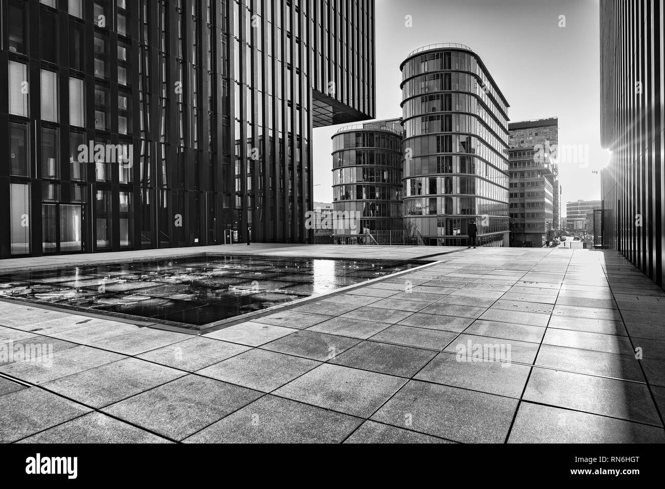 Duesseldorf, GERMANY - January 20, 2019: Modern architecture of New Harbour City throws long and dramatic shadows during sunset captured in B W. Stock Photo