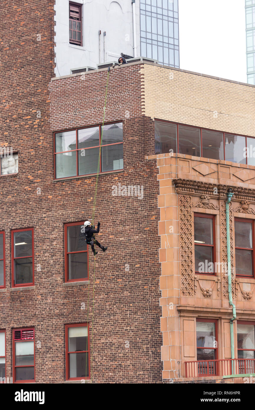 Industrial engineer rappelling down the side of a building on a