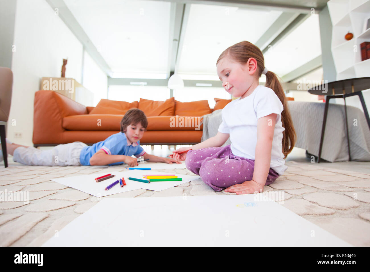 Little boy and girl drawing with color pencils on the floor playing ...