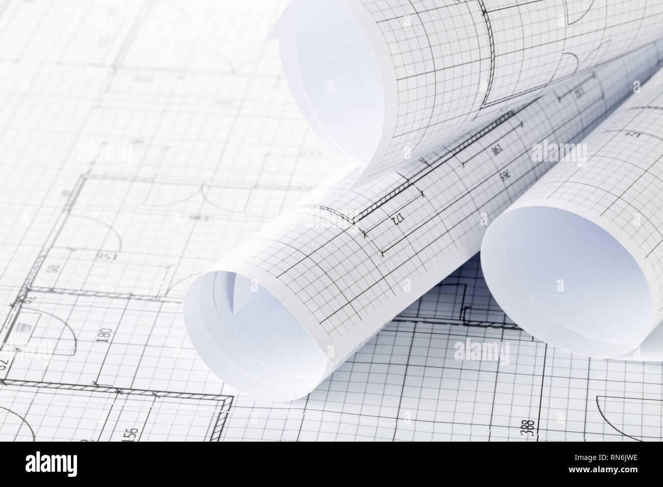 Rolls of architectural blueprint house building plans on blueprint background on table Stock Photo
