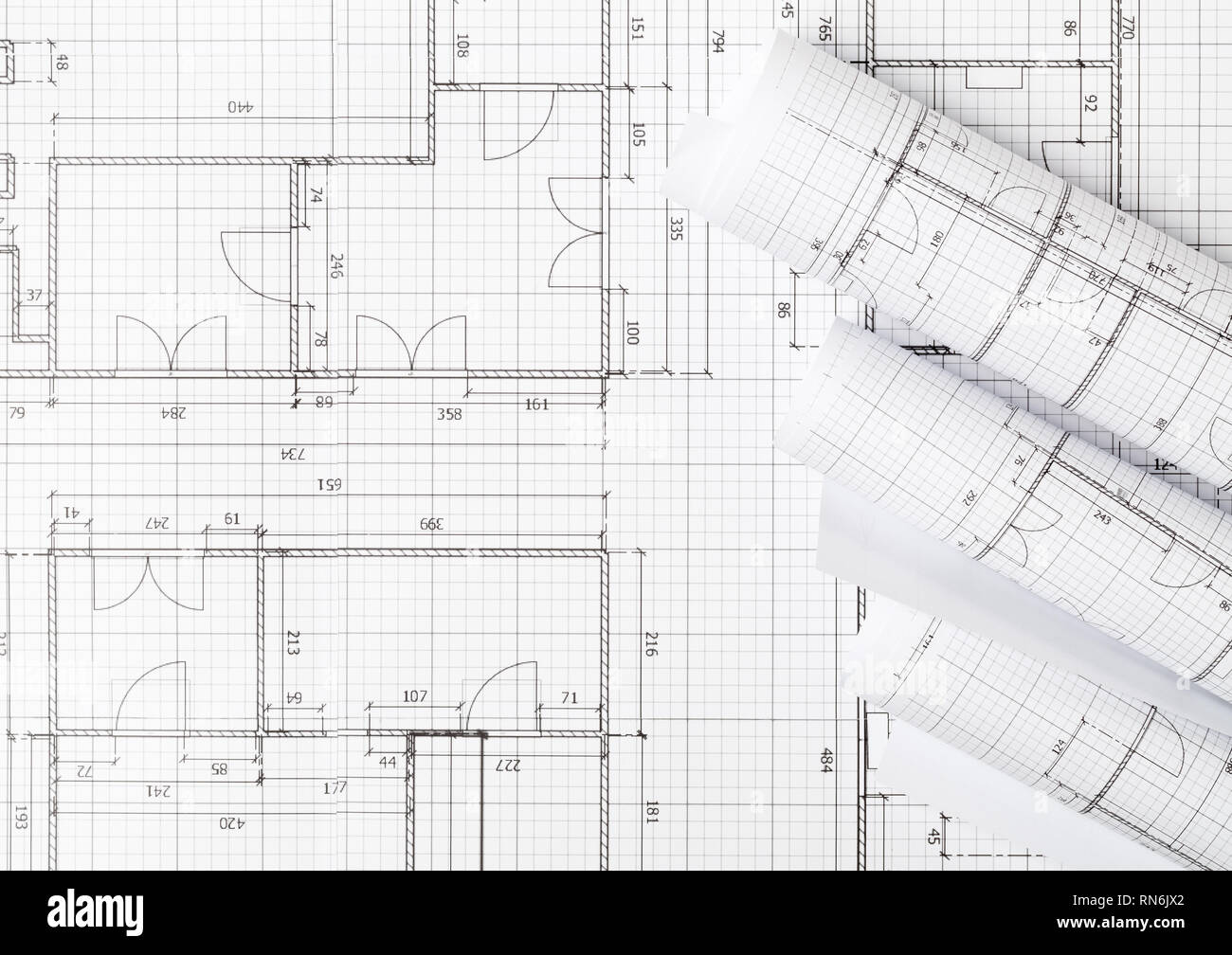 Rolls of architectural blueprint house building plans on blueprint background on table flatlay top view from above Stock Photo