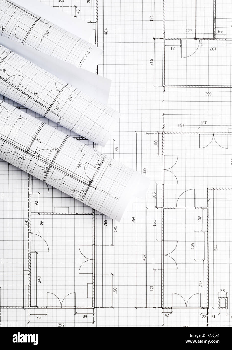 Rolls of architectural blueprint house building plans on blueprint background on table flatlay top view from above Stock Photo