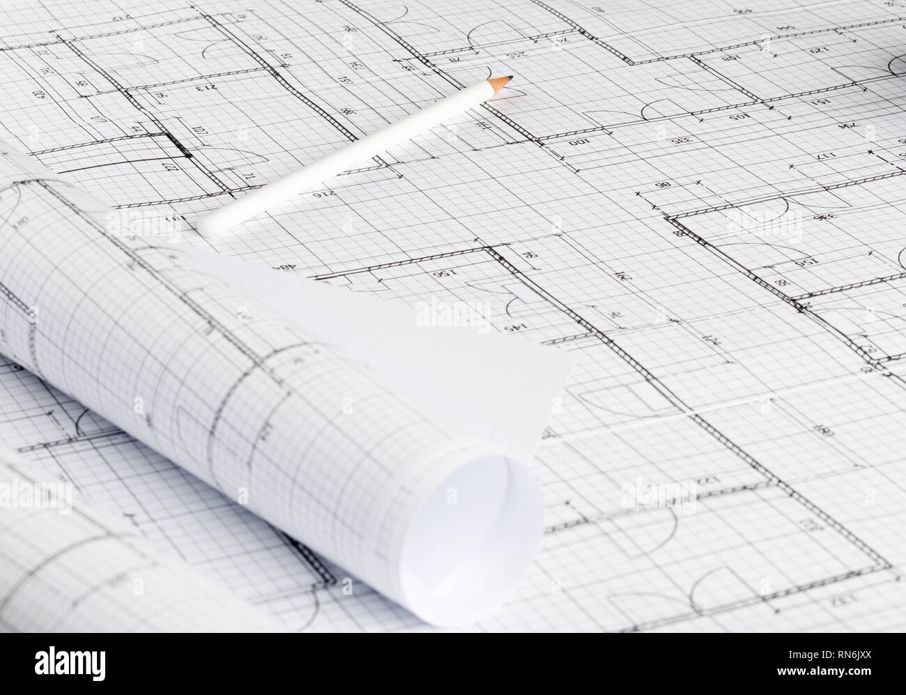 Rolls of architectural blueprint house building plans on blueprint background on table with pencil Stock Photo