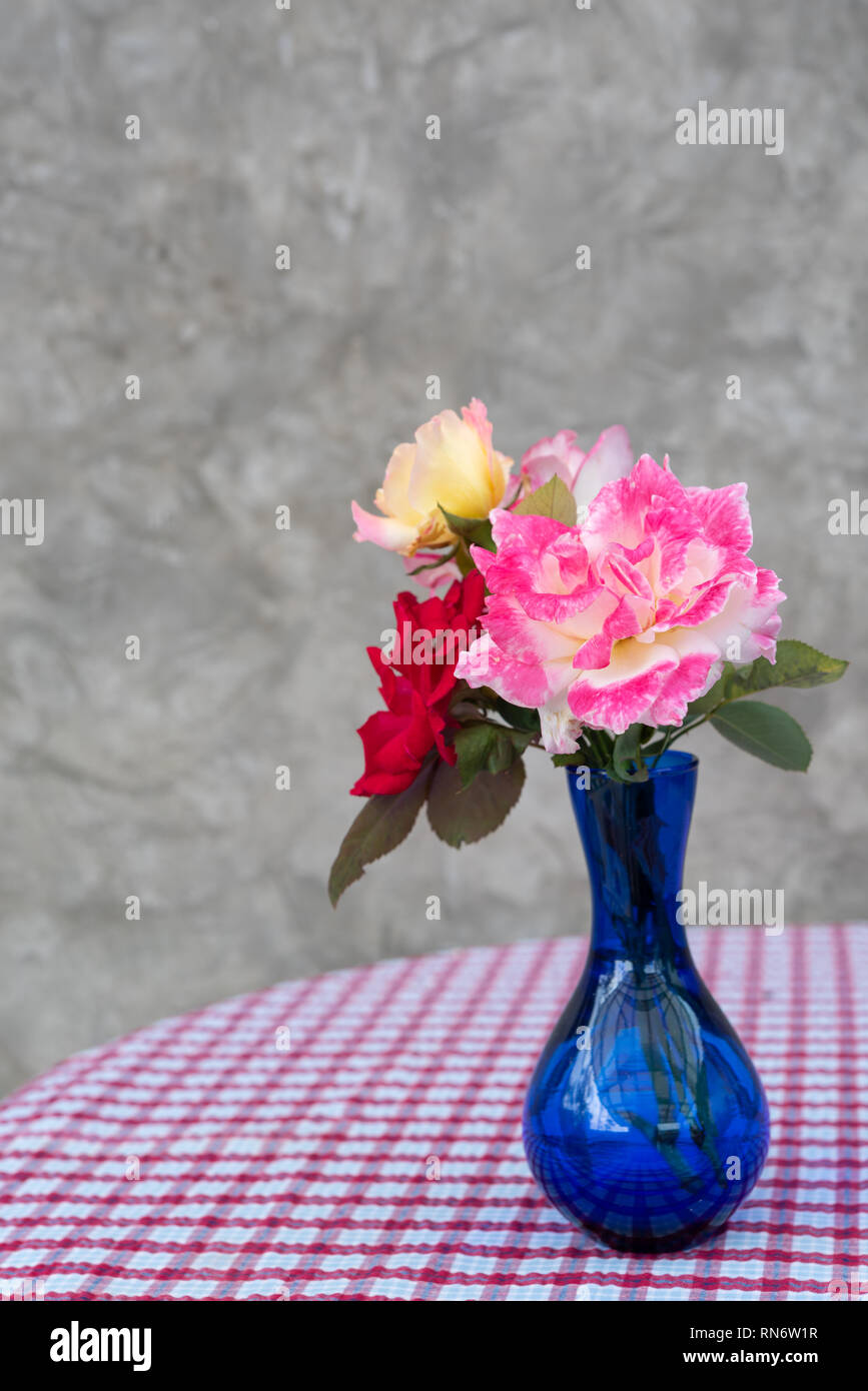 Beautiful red and pink roses in blue vase on red and white beautiful red and pink roses in blue vase on red and white checkered table backgroundstill life RN6W1R