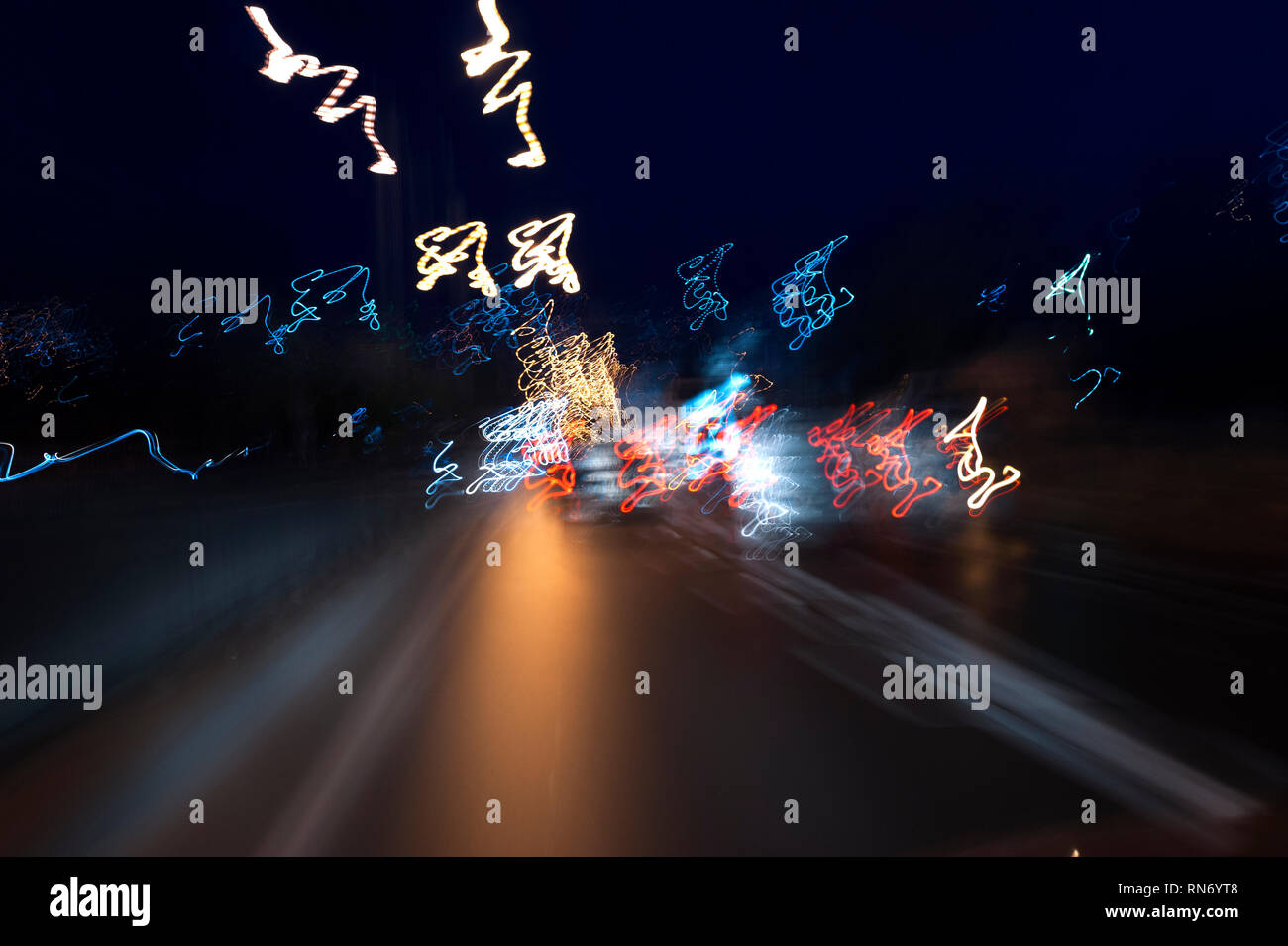 Looks like a view from eyes of a drunken driver, long exposure road photo at night abstract speeding background with cars. Stock Photo